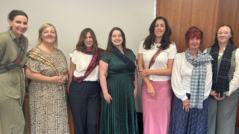 L&M Medilaw team standing in a row with small tartan scarves